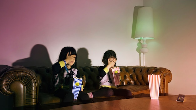 Foto gratuita ragazze spaventate con popcorn guardando la tv