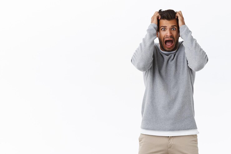 Free Photo scared guy in panic grab head and screaming stare camera popped eyes from fright afraid something trembling fear standing stupor shouting terrified standing white background frustrated