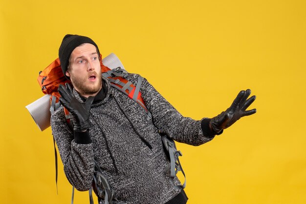 scared male hitchhiker with leather gloves and backpack staying away from something