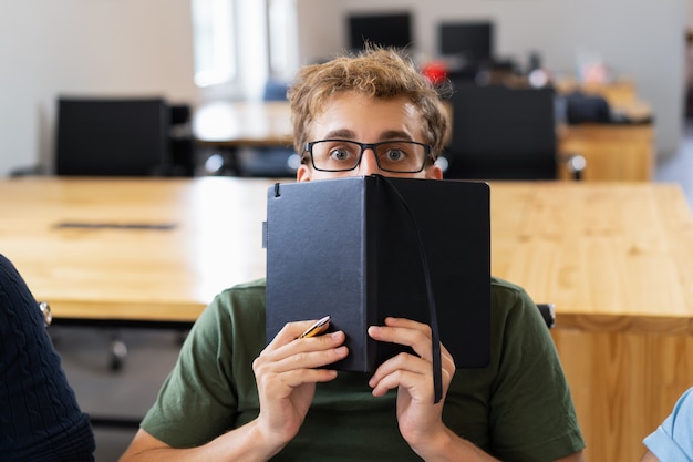 biography book layout Free photo scared male student hiding behind notebook