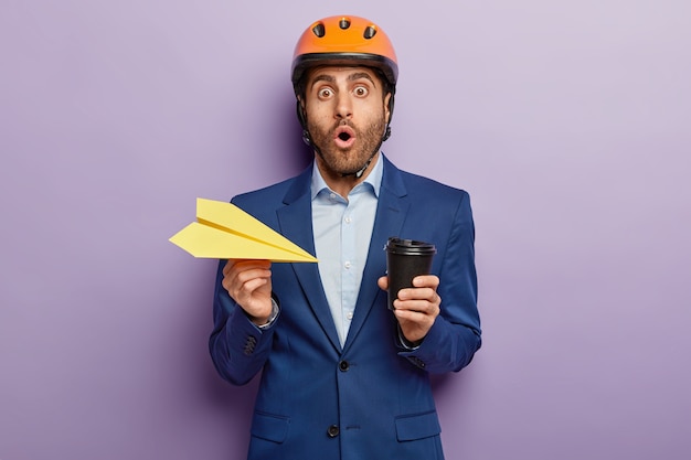 Scared male technician in safety helmet stares with omg expression