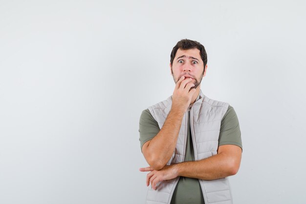 The scared man is holding his right hand to mouth on white background