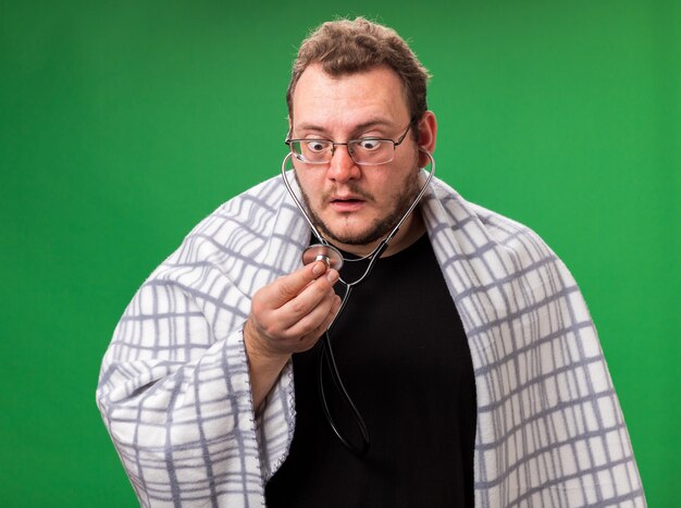 Scared middle-aged ill male wrapped in plaid listening to his own heartbeat 