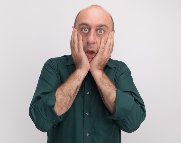 Scared middle-aged man wearing green t-shirt covered face isolated on white wall