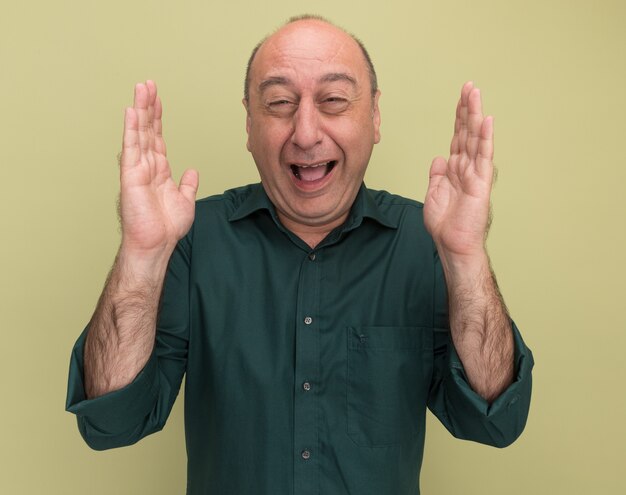 Scared middle-aged man wearing green t-shirt showing size isolated on olive green wall