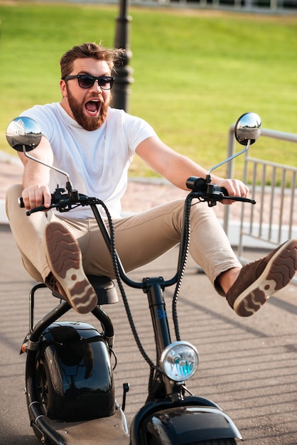 無料写真 現代のバイクを屋外に乗ってサングラスで怖がって叫んでいるひげを生やした男