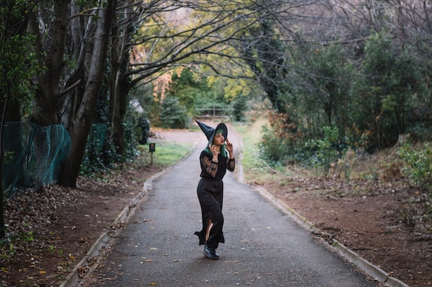 Scared witch walking along forest road