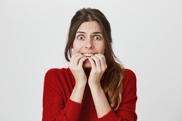 Scared woman biting fingernails in panic