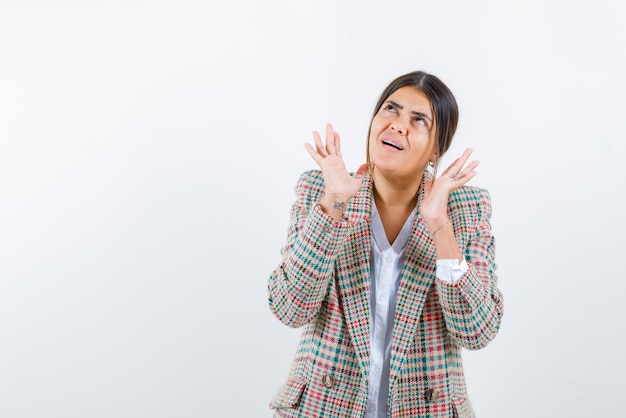 The scared woman is raising up her hands on white background