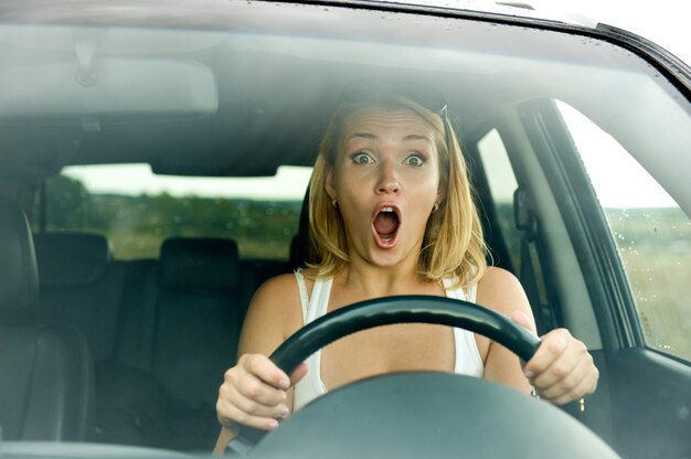 Scared woman shouts driving the car - outdoors