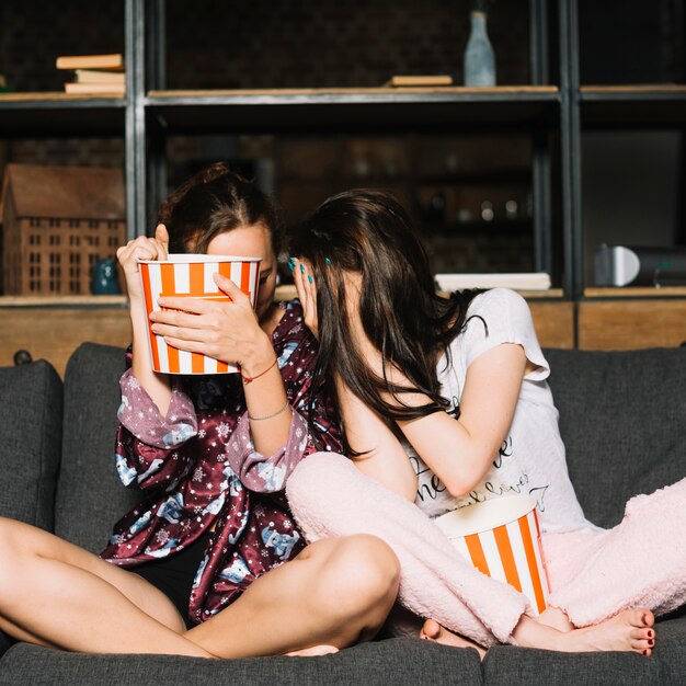 Scared women sitting on sofa hiding their face