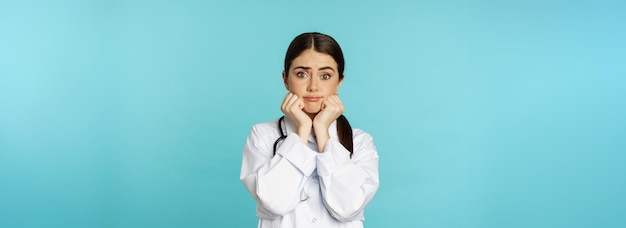 Scared and worried woman doctor in white coat looking anxious and insecure shaking from fear standin