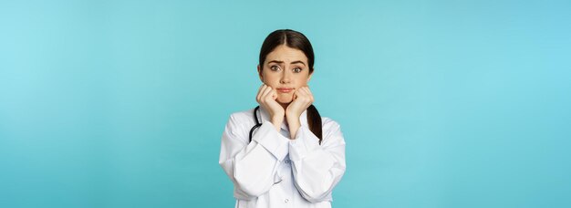 Scared and worried woman doctor in white coat looking anxious and insecure shaking from fear standin