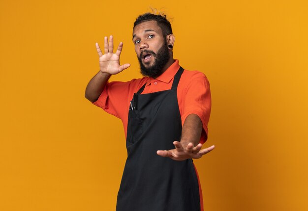 Scared young afro-american male barber wearing uniform doing refusal gesture 