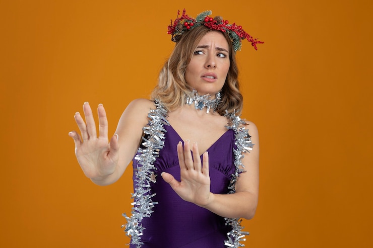 Free Photo scared young beautiful girl wearing purple dress with wreath holding out hands at side isolated on brown background