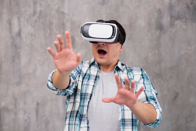 Испуганный молодой человек с поднятыми руками в гарнитуру VR