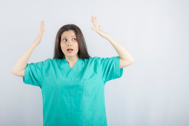 Scared young medical worker. Holding her hands up.