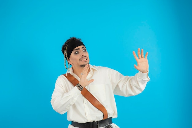 Free photo scared young pirate stand on blue background and looking aside. high quality photo