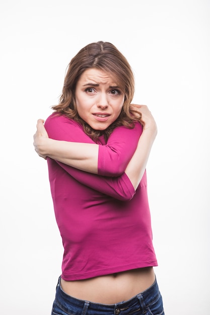 Scared young woman hugging herself against white background