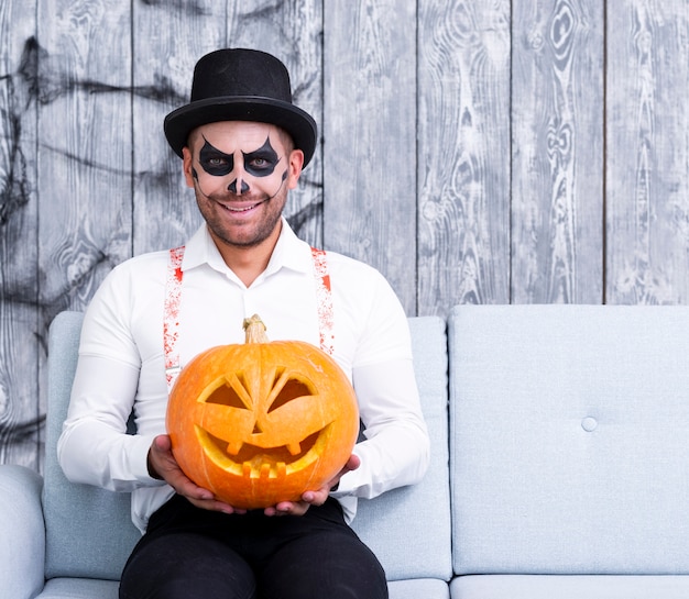 Free photo scary adult man holding carved pumpkin