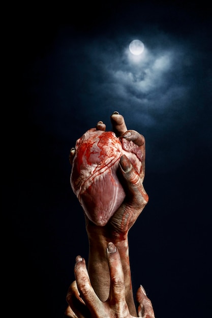 Scary female zombie hands holding a heart