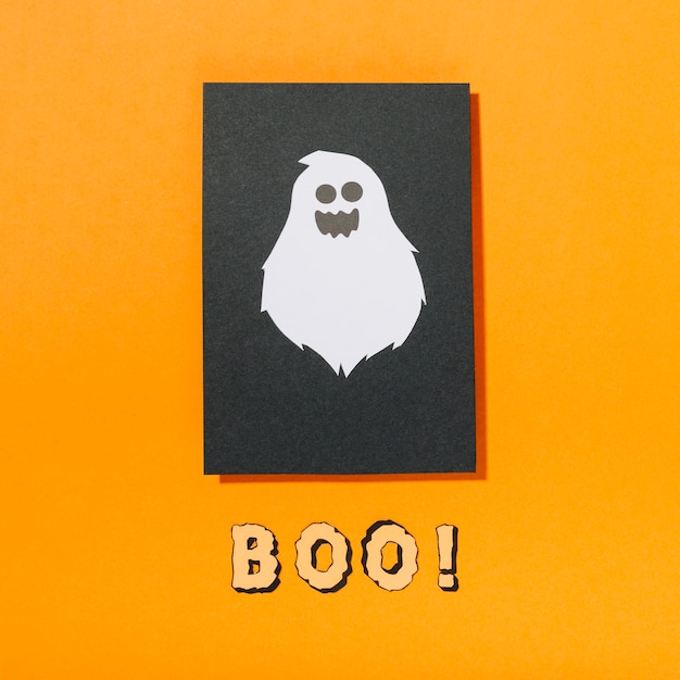 Foto gratuita spaventoso fantasma su un pezzo di carta nera con boo! iscrizione qui sotto