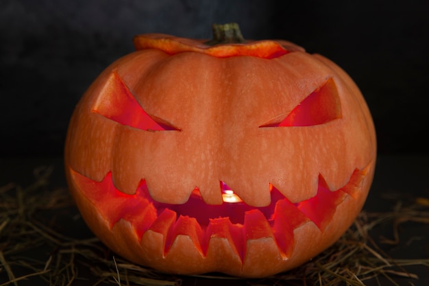 Foto gratuita lanterna di zucca intagliata di halloween spaventoso con faccia spettrale