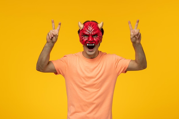 Free photo scary mask young terrifying guy making peace sign with open mouth