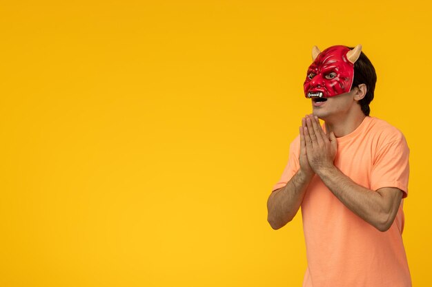 Страшная маска, молодой ужасающий парень, молящийся в злой красной маске