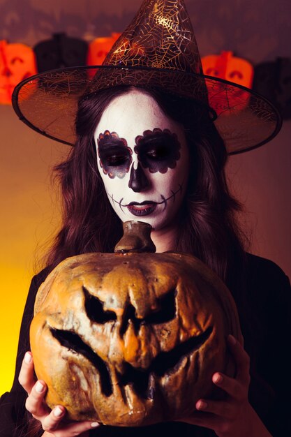 Scary witch holding pumpkin