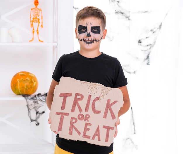 Scary young boy holding trick or treat sign