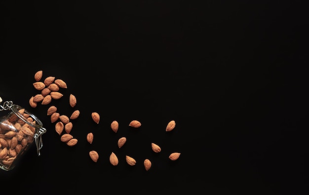 Scattered almond nuts on a black background flat lay