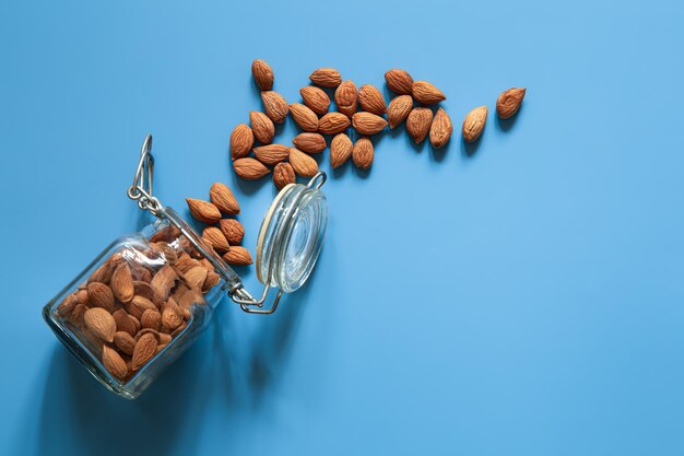 Scattered almond nuts on a blue background flat lay