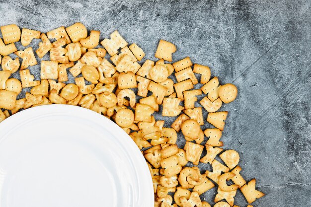 Scattered alphabet crackers around a empty plate.