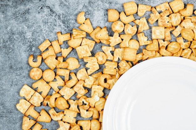 Scattered alphabet crackers around a empty plate.