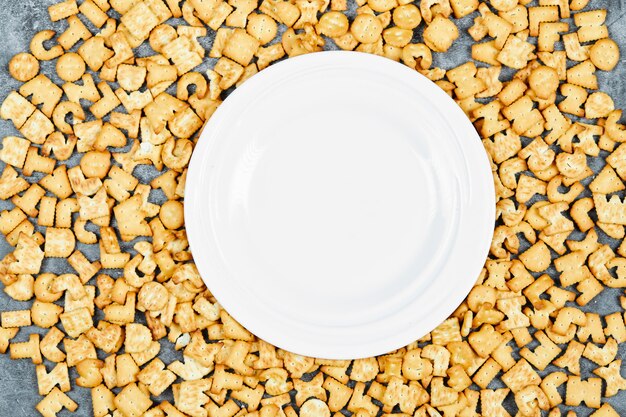 Scattered alphabet crackers around a empty plate.