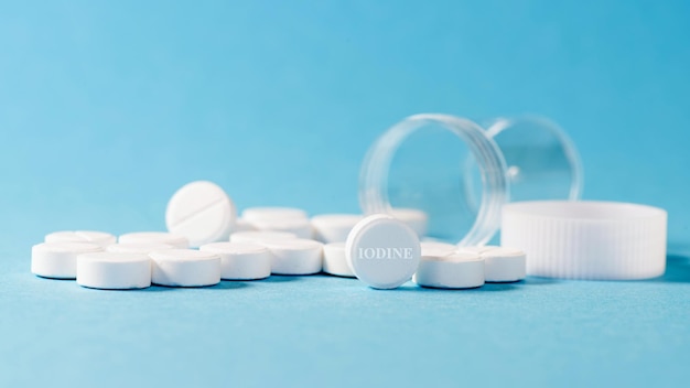 Scattered antiradiation iodine pills an empty jar blue background