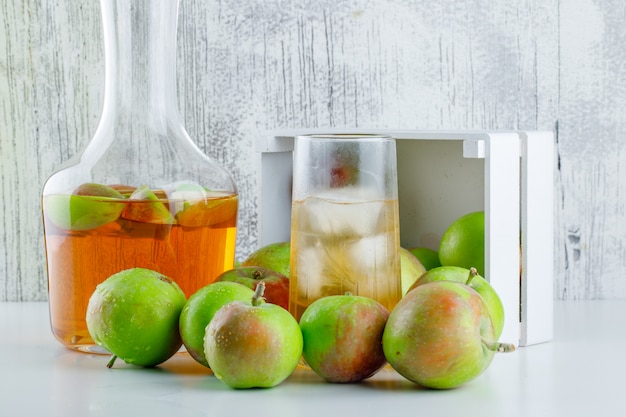 Scattered apples from a wooden box with drink side view on white and grungy