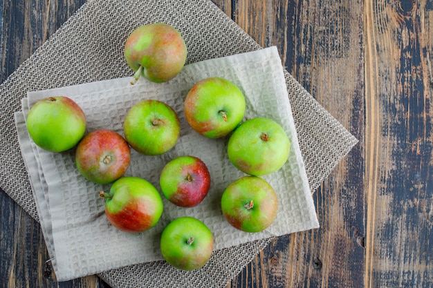 Scattered apples with kitchen towel on wooden and placemat background, flat lay.