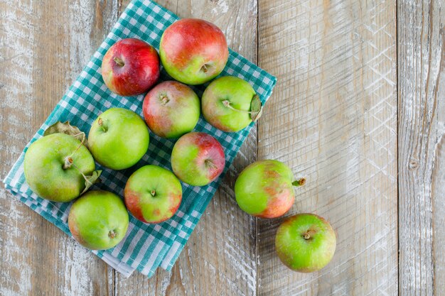Scattered apples on wooden and picnic cloth.