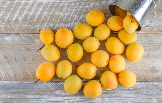 Scattered apricots from mini bucket on a wooden table. flat lay.