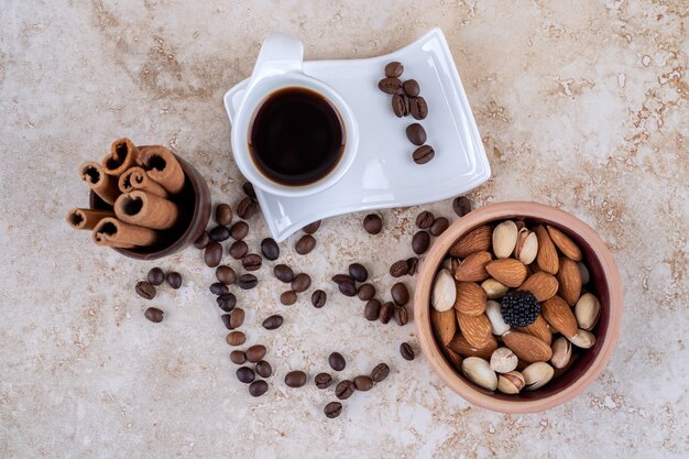 흩어져있는 커피 원두, 모듬 견과류, 번들 시나몬 스틱 및 커피 한 잔