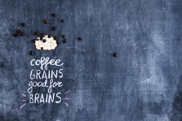 Scattered coffee beans on paper cutout brain with text on chalkboard