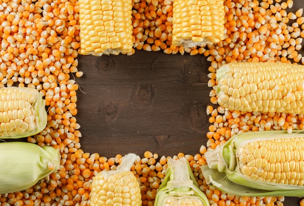 Scattered corn grains with cobs flat lay on a wooden table