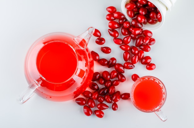 Scattered cornel berries from a bowl with drink on white