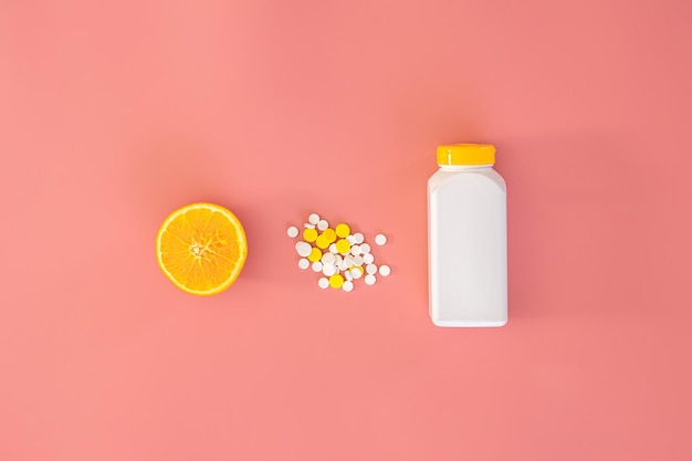 Scattered pills on pink background orange vitamin c concept flat lay