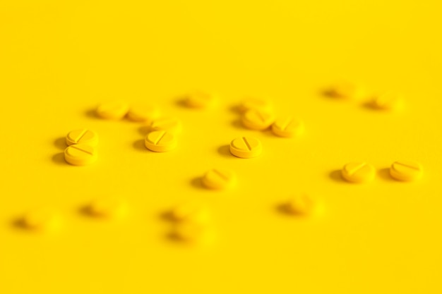 Scattered pills over the yellow background