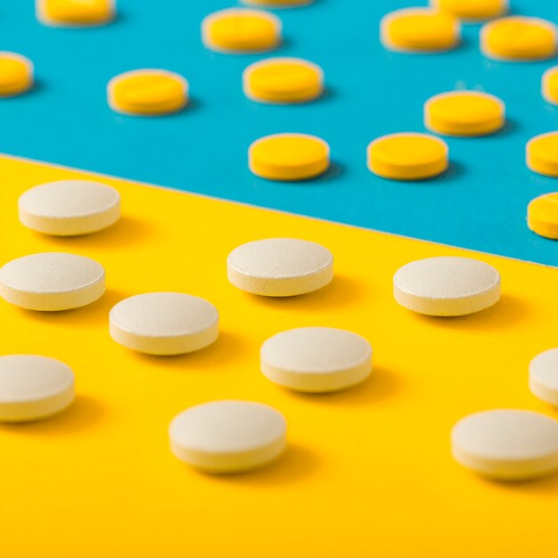 Scattered pills on yellow and blue background