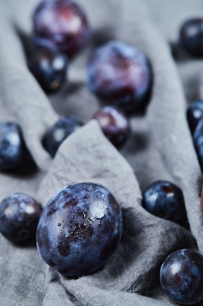 Free photo scattered plums on gray tablecloth.