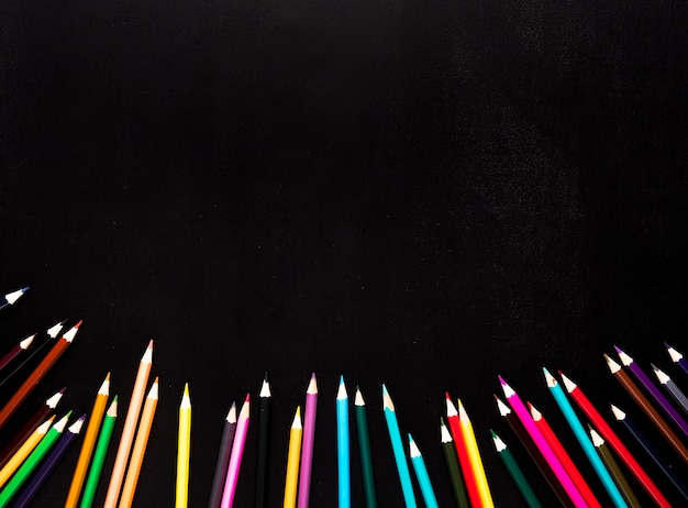 Free photo scattered sharpened color pencils placed in bottom of black background